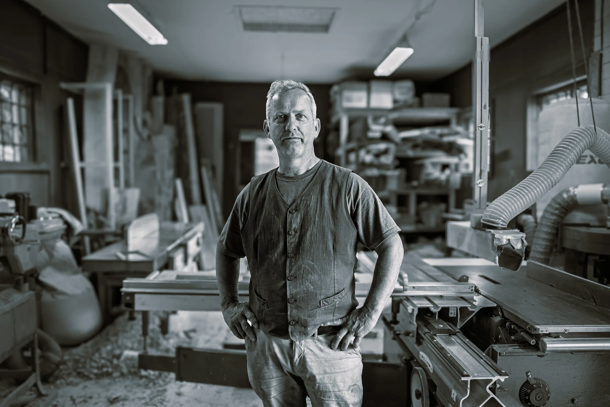 Black and white portrait of a woodworker standing in his workshop at Ljan Stasjon, Oslo, Norway
