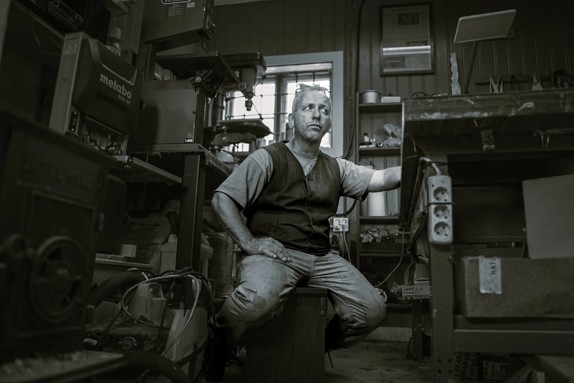 Black and white portrait of a woodworker beside his workbench at Ljan Stasjon, Oslo, Norway
