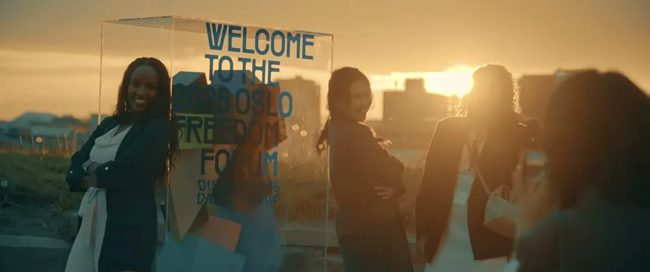 Welcome sign for the 2026 Oslo Freedom Forum backlit at sunset with attendees in silhouette